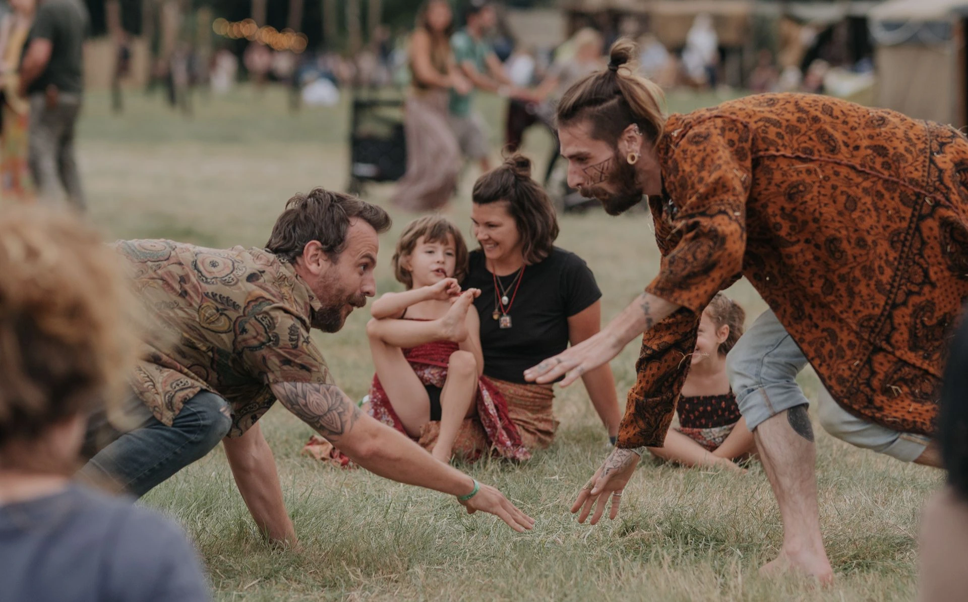 Outdoor movement play session with people interacting on a grassy field during a family-friendly workshop or festival.