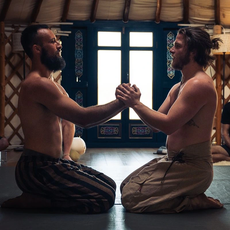 Two people participating in a partner mindfulness and connection exercise inside a yurt studio.