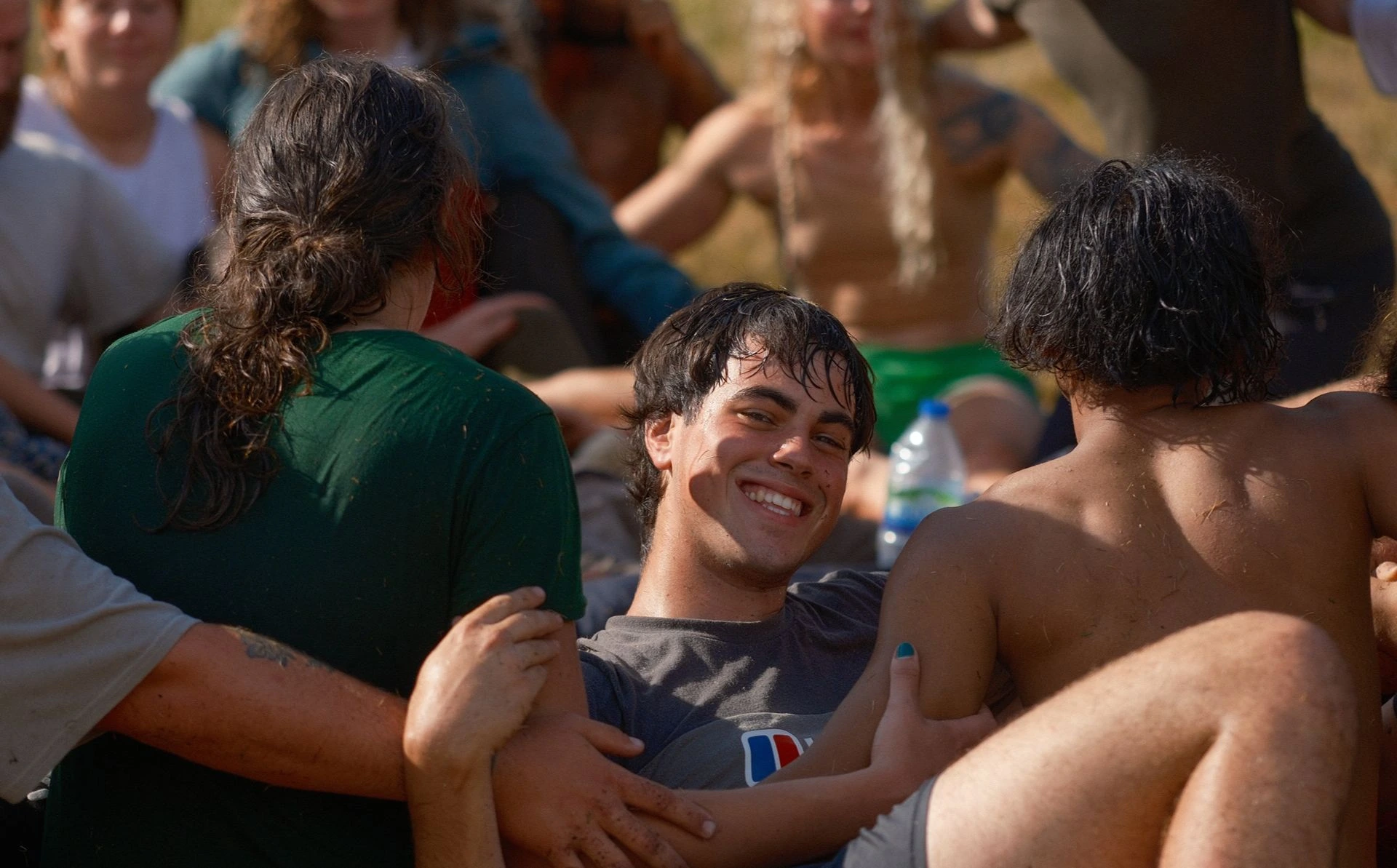 Smiling participant leaning back while supported by other participants during an outdoor group play activity.