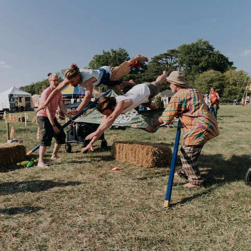 Participants jumping over a stretched banner during a playful outdoor group activity.